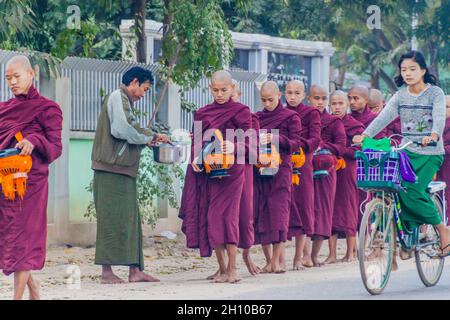 BAGAN, MYANMAR - 8. DEZEMBER 2016: Reihen buddhistischer Mönche mit Schalen, die ihre täglichen Almosen sammeln. Stockfoto