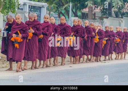 BAGAN, MYANMAR - 8. DEZEMBER 2016: Reihen buddhistischer Mönche mit Schalen, die ihre täglichen Almosen sammeln. Stockfoto