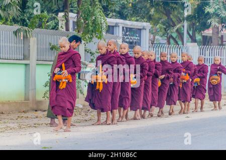 BAGAN, MYANMAR - 8. DEZEMBER 2016: Reihen buddhistischer Mönche mit Schalen, die ihre täglichen Almosen sammeln. Stockfoto