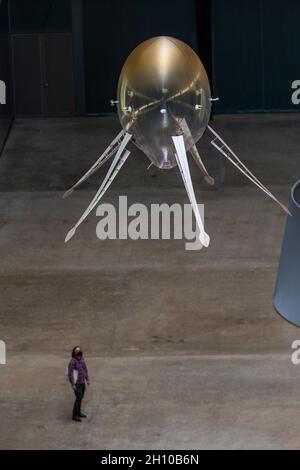 London, Großbritannien. 15. Oktober 2021. Die Besucher sehen schwebende Kunstflugkörper, die Anicka Yis neues Luftwerk „in Love With The World“ bilden, in der Turbine Hall of Tate Modern für die Hyundai-Kommission 2021. Die Installation besteht aus Maschinen, die als Kunstflugkörper bezeichnet werden, basierend auf Lebensformen des Ozeans und Pilzen, die in der Luft schweben, und stellt eine Neueinbildung dar, wie künstliche Intelligenz und neue Maschinen die Welt bewohnen könnten. Die Arbeit kann bis zum 16. Januar 2022 erlebt werden. Kredit: Stephen Chung / Alamy Live Nachrichten Stockfoto