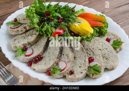 Fischgericht: Fischfilet mit Gemüse und Kräutern aus der Nähe auf einem weißen Teller auf dunklem Holzboden Stockfoto