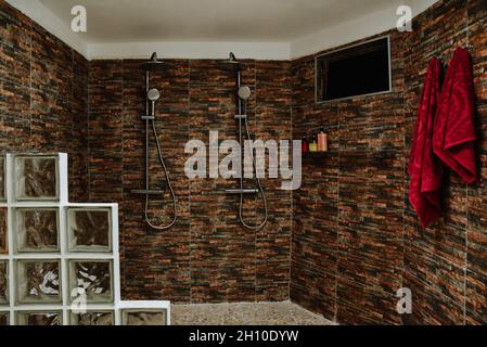 Aufnahme des Innenraums eines Duschraums mit Fernseher und roten Handtüchern an braunen Wänden Stockfoto