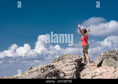 Frau, die von einem Berggipfel auf das Tal herabblickt Stockfoto