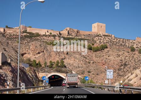 Burg von Lorca, oberhalb des Straßentunnels A-7 in Lorca, Region Murcia, Spanien. Historisches Castillo de Lorca Wahrzeichen hoch über der Autobahnausfahrt Stockfoto