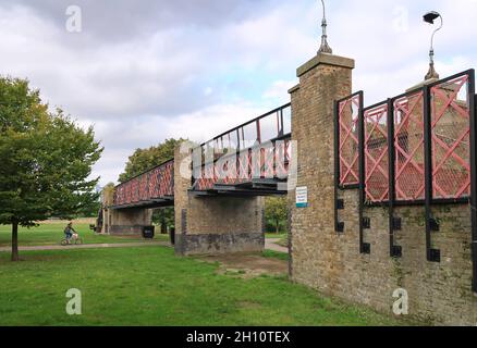 Burgess Park, Peckham, London, Großbritannien. Radfahrer und Fußgänger auf einem Weg entlang der alten Surrey Canal Route. Zeigt die originale viktorianische Kanalbrücke. Stockfoto