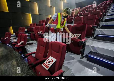 Quezon, Philippinen. Oktober 2021. Ein Mitarbeiter legt in einem Kino, das für die Öffentlichkeit in einem Einkaufszentrum in Quezon City, Philippinen, wieder geöffnet wird, Schilder an soziale Distanzierungen, am 15. Oktober 2021. Die philippinische Regierung wird ab dem 16. Oktober damit beginnen, die Sperrbeschränkungen in Metro Manila zu lockern, sodass mehr öffentliche Einrichtungen in der Hauptstadt mit begrenzten Kapazitäten betrieben werden können. Quelle: Rouelle Umali/Xinhua/Alamy Live News Stockfoto