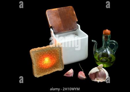Stillleben von Toast, Knoblauch, Öl und Salz auf schwarzem Hintergrund. Stockfoto