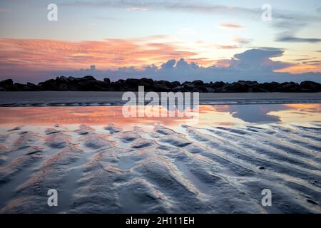 Sandmuster und Reflexionen eines Gezeitenpools bei Sonnenaufgang - Driftwood Beach - Jekyll Island, Georgia, USA Stockfoto