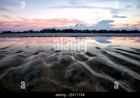 Sandmuster und Reflexionen eines Gezeitenpools bei Sonnenaufgang - Driftwood Beach - Jekyll Island, Georgia, USA Stockfoto