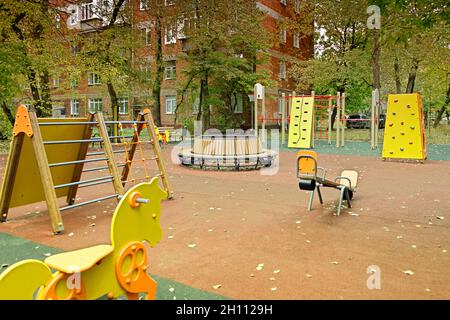 Leerer Kinderspielplatz. Kinderkomplex mit verschiedenen Schaukeln im Innenhof. Das Konzept der gesunden Erholung und der Entwicklung der Kinder. Stockfoto