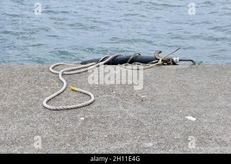 Nautisches Bild eines alten gewickelten Seils am Kai neben dem Hafen Stockfoto