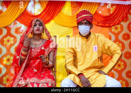 Neu-Delhi, Indien. Oktober 2021. Die in traditionellem roten Saree getrackte Braut sitzt während der Trauung mit dem Bräutigam in Maske auf der Bühne. Lions Club Delhi Karan organisierte eine Samuhik Viva (Massenhochzeit) für wirtschaftlich schwächere Gebiete in Sarva Sanatan Shiv Mandir, Trilokpuri. Kredit: SOPA Images Limited/Alamy Live Nachrichten Stockfoto