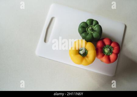 High-Angle-Schuss von drei verschiedenen farbigen Paprika auf einem Kunststoffbrett Stockfoto