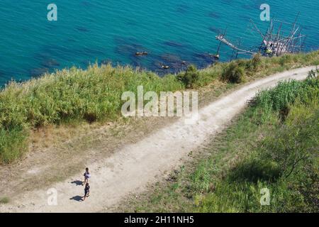 Ein junges Paar reist auf einer unbefestigten Straße zu einem kleinen Strand an der Küste der Abruzzen. Trabocchi-Küste, Abruzzen, Italien Stockfoto