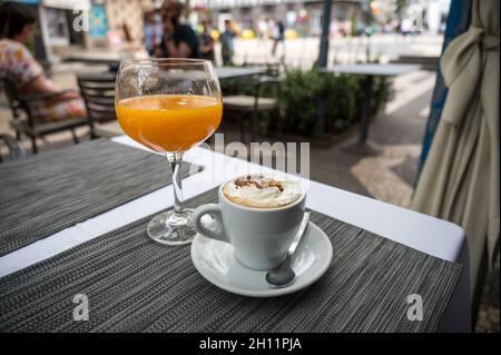 Tasse Kaffee mit frisch gepresstem Orangensaft auf einem Tisch. Stockfoto