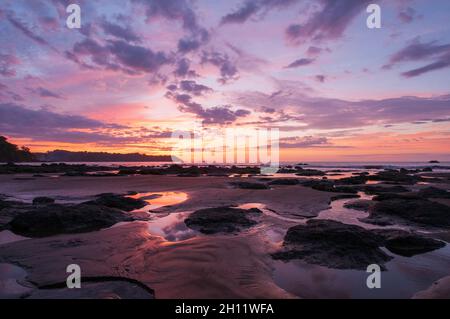 Wasserpfützen und Sandhaufen am Strand bei Sonnenuntergang. Drake Bay, Osa Peninsula, Costa Rica. Stockfoto