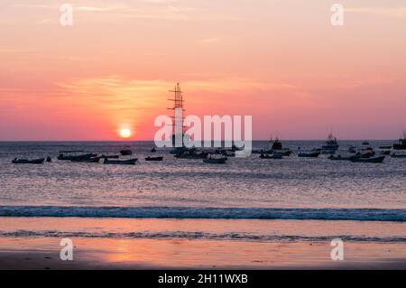 Das Star Flyer Segelkreuzfahrtschiff und kleine Boote ankerten bei Sonnenuntergang vor der Küste. San Juan del Sur, Nicaragua. Stockfoto