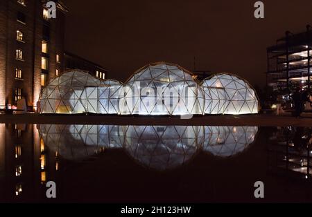 London, Großbritannien. Oktober 2021. Pollution Pods von Michael Pinsky spiegeln sich in den Brunnen vor Central Saint Martins am Granary Square, King's Cross. Die Installation besteht aus fünf geodätischen Kuppeln, die jeweils eine andere Umgebung und Luftqualität enthalten, und ermöglicht es den Besuchern, die saubere Luft von Tautra in Norwegen und die Verschmutzung von Neu Delhi, Peking, Sao Paulo und London zu erleben. Kredit: Vuk Valcic / Alamy Live Nachrichten Stockfoto