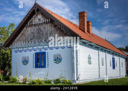 Zalipie, Polen - 1. August 2021: Ein traditionelles, weißes Holzhaus mit Wänden, die in farbenfrohen Blumenmustern gemalt sind. Stockfoto