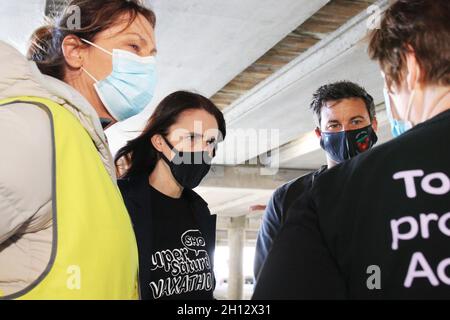 Wellington, Neuseeland. 16. Oktober 2021. Die neuseeländische Premierministerin Jacinda Ardern, zweite von links, mit ihrer Partnerin Clarke Gayford spricht mit Impfern bei einer Fahrt durch das Impfzentrum Covid-19, das im Sky Stadium für den „Super Saturday Vaxathon“ eingerichtet wurde. Quelle: Lynn Grieveson/Alamy Live News Stockfoto