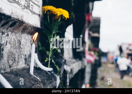 Brennende Kerze, die vor dem Wohnzimmergrab bei einem Besuch des Grabes eines verstorbenen Familienmitglieds aufgestellt wurde. Selektiver Fokus. Speicherplatz kopieren. Stockfoto