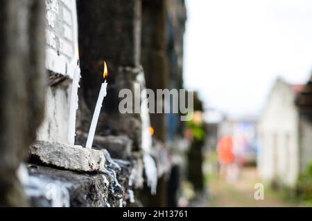 Brennende Kerze, die vor dem Wohnzimmergrab bei einem Besuch des Grabes eines verstorbenen Familienmitglieds aufgestellt wurde. Selektiver Fokus. Speicherplatz kopieren. Stockfoto