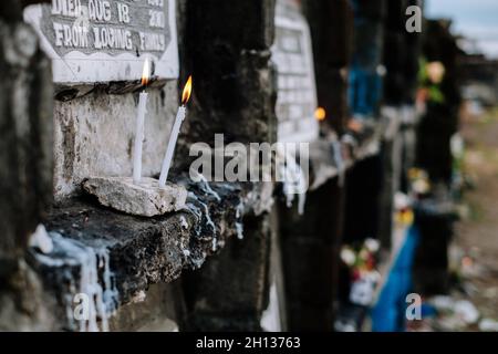 Brennende Kerze, die vor dem Wohnzimmergrab bei einem Besuch des Grabes eines verstorbenen Familienmitglieds aufgestellt wurde. Selektiver Fokus. Speicherplatz kopieren. Stockfoto