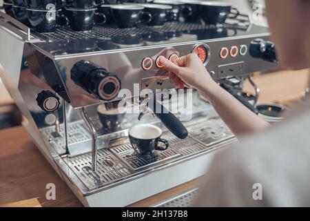 Junge Barista mit moderner Kaffeemaschine in der Cafeteria Stockfoto