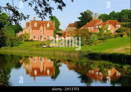 Farbenfrohe Häuser im Dorf Kintbury und Reflexionen im Kennet- und Avon-Kanal kurz vor Sonnenuntergang in Kintbury, Bekshire, England Stockfoto