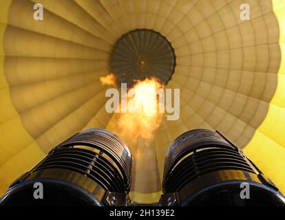 Flammen kommen vom Brenner in einen gelben Heißluftballon, in der Nähe des Füllens eines Heißluftballons Stockfoto