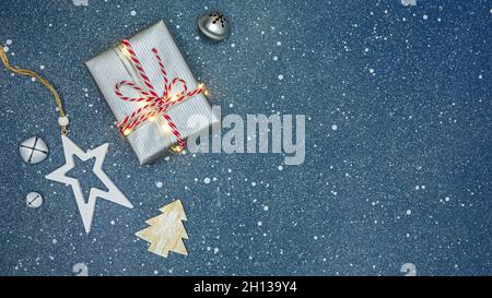 weihnachten Urlaub Thema. Silber Geschenkbox von glühenden Weihnachtsbeleuchtung mit weihnachtsornamenten auf blauem Hintergrund dekoriert. Stockfoto