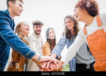 Portrait von glücklichen Universitätsfreunden, die sich die Hände stapeln, Einheit und Zweisamkeit zeigen - vielfältige Kultur Studenten feiern zusammen - Freunde Stockfoto