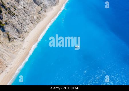 Lefkada, Griechenland. Abgelegener weißer Egremni-Strand mit einsamem Luxus-Yacht-Boot an der türkisfarbenen Bucht am Ionischen Meer Stockfoto
