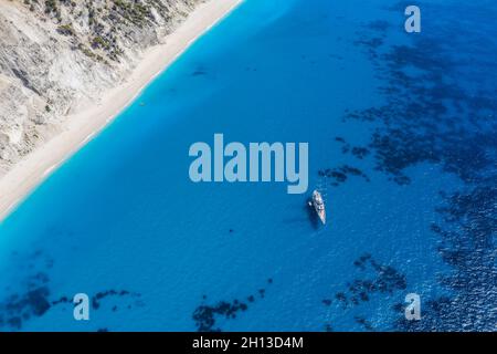 Lefkada, Griechenland. Abgelegener weißer Egremni-Strand mit einsamem Luxus-Yacht-Boot an der türkisfarbenen Bucht am Ionischen Meer Stockfoto