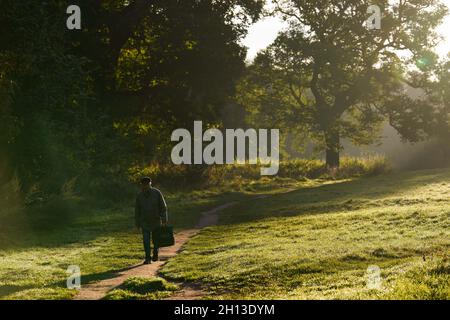 Ein Mann spaziert während des Sonnenaufgangs in Warwick, Warwickshire, durch den Priory Park. Bilddatum: Samstag, 16. Oktober 2021. Stockfoto