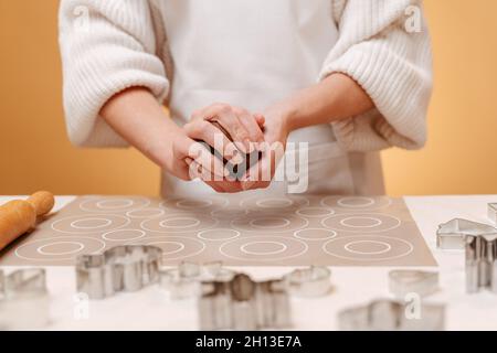 Eine Frau auf gelbem Hintergrund knetet Ingwerteig-Kekse. Stockfoto