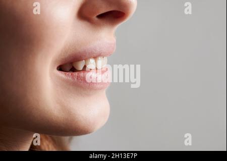 Beschnittene Nahaufnahme des Lächelns einer schönen Frau, die gesunde Zähne zeigt. Seitenansicht. Space Image kopieren. Konzept der Mundhygiene Stockfoto
