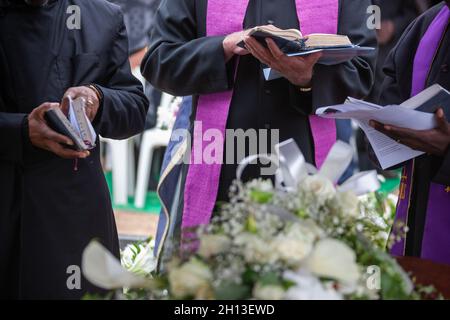 Drei anglikanischen Priester an einer Beerdigung, neben dem Grab Stockfoto