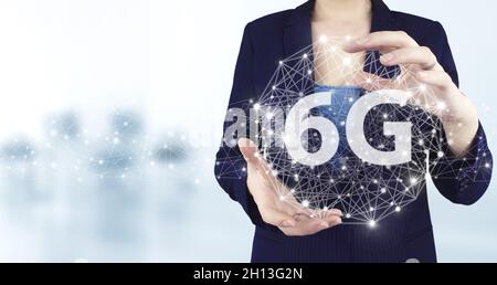 6G Network Internet Mobile Wireless Business Concept. Virtuelles holographisches 6G-Symbol mit zwei Händen und hellem unscharfem Hintergrund. Abstrakte Welt netwo Stockfoto