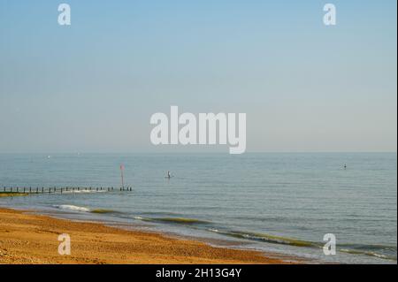 Zwei Paddlebarder auf See bei warmem Sonnenschein am Oktobernachmittag mit sanften Wellen, die gegen Hove Beach, East Sussex, England, brechen. Stockfoto