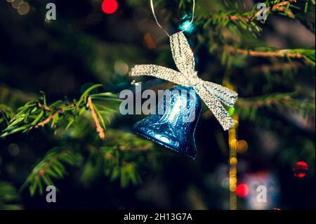 Silvester oder Weihnachten lebhaft elegant dekoriert FichtenNahaufnahme - Weihnachtsspielzeug vor dem Hintergrund von grünen Ästen und Lichtern. Stockfoto