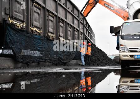 (211016) -- QIAN'AN, 16. Oktober 2021 (Xinhua) -- Arbeiter entladen Koks aus einem Zug auf einem Logistikhof in Qian'an, nordchinesische Provinz Hebei, 16. September 2021. Qian'an in der Provinz Hebei ist ein wichtiger Landkreis in der Stahlindustrie in Nordchina, mit einer großen Transportnachfrage nach Rohstoffen wie Eisenerz, Kohle und Koks. Um die Umweltverschmutzung und die Verkehrsstaus durch den Straßentransport von Massengütern zu verringern, wurden spezielle Eisenbahnlinien für wichtige Eisen- und Stahlunternehmen im Rahmen eines „Road-to-Rail“-Systems gebaut, das den Weg für eine umweltfreundlichere und effizientere Logistik ebnete Stockfoto