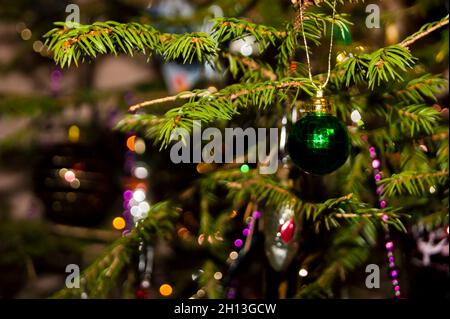 Silvester oder Weihnachten lebhaft elegant dekoriert FichtenNahaufnahme - Weihnachtsspielzeug vor dem Hintergrund von grünen Ästen und Lichtern. Stockfoto