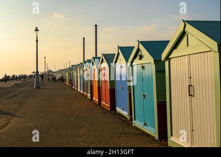 Eine Reihe von bunten Strandhütten, die im weichen, warmen Licht des Oktobernachmittages an der Strandpromenade von Hove, East Sussex, England, glühen. Stockfoto