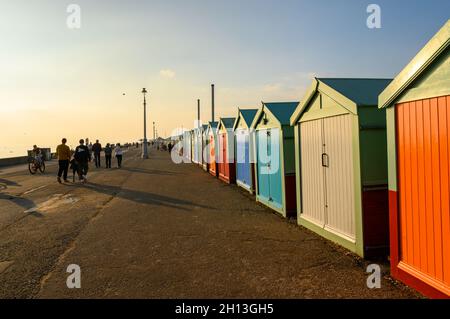 Eine Reihe von bunten Strandhütten, die im weichen, warmen Licht des Oktobernachmittages an der Strandpromenade von Hove, East Sussex, England, glühen. Stockfoto