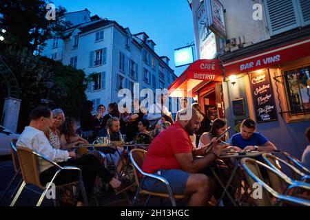 Paris, Frankreich - Juli 2019: Franzosen und Touristen sitzen und bestellen auf einer Franch-Bistrot-Terrasse in Montmatre, in der Nähe des Moulin de la Galette Stockfoto