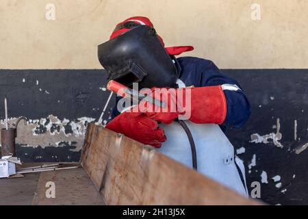 Motswana Schweißgerät Arbeiter in einer Botswana Workshop, Schweißen zwei Teile aus Metall Stockfoto