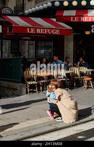 Paris, Frankreich - 2019. Juni: Eine Frau trägt im Sommer ihr Kind auf der Straße vor der Metrostation Lamarck-Colaincourt in Montmartre. . O Stockfoto