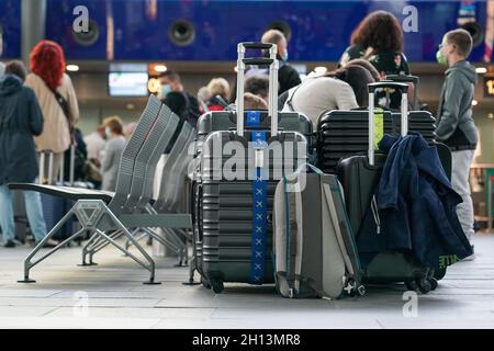 Schkeuditz, Deutschland. Oktober 2021. Reisende warten mit ihrem Gepäck beim Check-in am Flughafen Leipzig/Halle. Das erste Wochenende der Herbstferien in Sachsen ist eine geschäftige Zeit am Flughafen. Insgesamt starten am Samstag und Sonntag 50 Flugzeuge von den Flughäfen Leipzig/Halle und Dresden in Sachsen zu Urlaubszielen wie Spanien, der Türkei, Griechenland und Italien. Kredit: Peter Endig/dpa-Zentralbild/dpa/Alamy Live Nachrichten Stockfoto