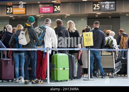 Schkeuditz, Deutschland. Oktober 2021. Reisende warten mit ihrem Gepäck beim Check-in am Flughafen Leipzig/Halle. Das erste Wochenende der Herbstferien in Sachsen ist eine geschäftige Zeit am Flughafen. Insgesamt starten am Samstag und Sonntag 50 Flugzeuge von den Flughäfen Leipzig/Halle und Dresden in Sachsen zu Urlaubszielen wie Spanien, der Türkei, Griechenland und Italien. Kredit: Peter Endig/dpa-Zentralbild/dpa/Alamy Live Nachrichten Stockfoto